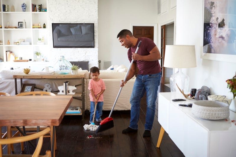 A father/grandfather and little boy sweep a living room floor
