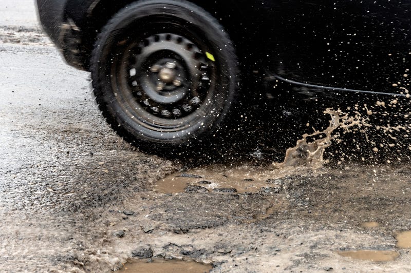 car drives over a pothole