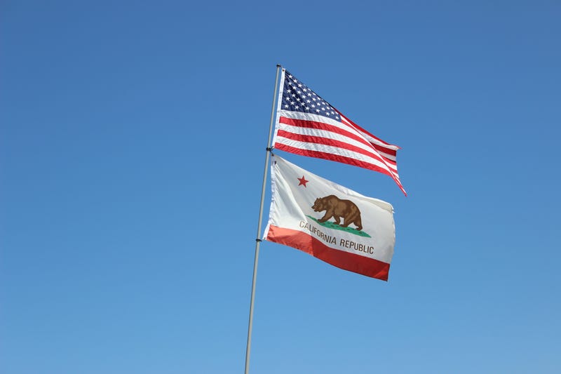 A flag pole with the USA and California state flags on it.