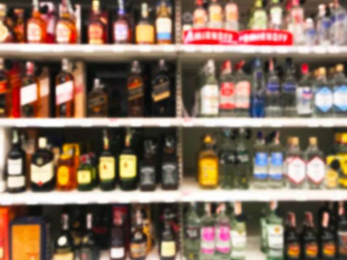 a burred image shows liquor bottles on a store shelf
