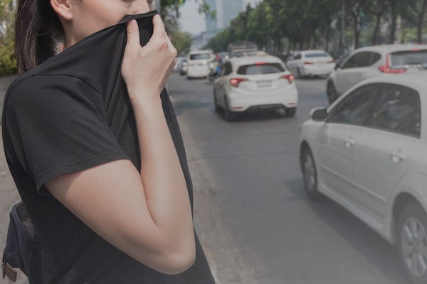 Woman covers mouth with shirt due to bad traffic pollution