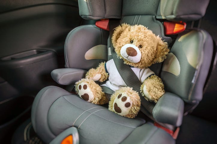 Teddy bear strapped into a child's car seat.