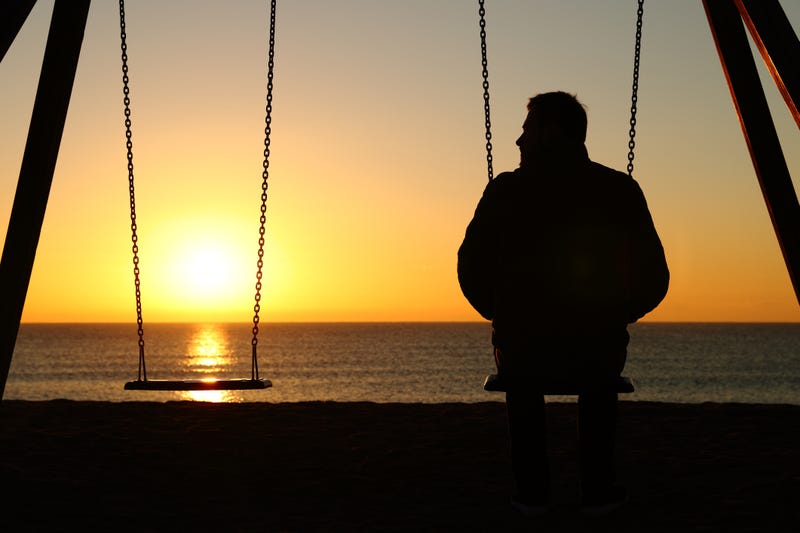 Man alone on a swing remembering someone he lost.