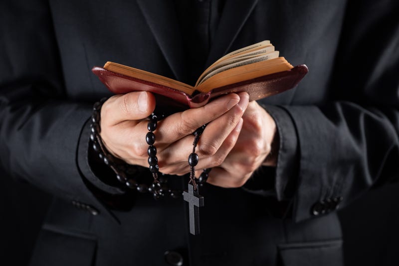 stock image of a priest holding a bible and rosary beads