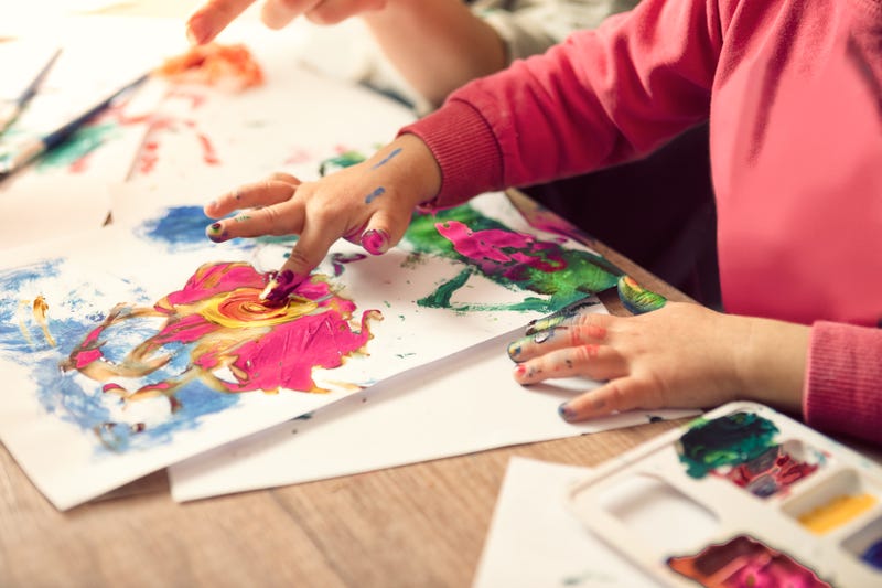 A child uses their fingers to paint.
