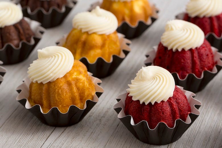 Mini bundt cakes with cream cheese icing on a wooden table