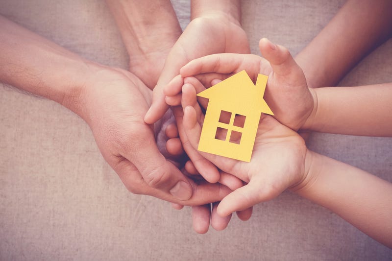 Adult and child hands holding yellow house