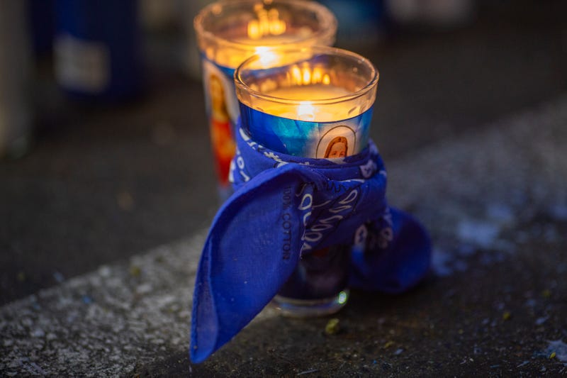 A blue bandana, symbol of the Crips gang, wrapped around a candle at a memorial.