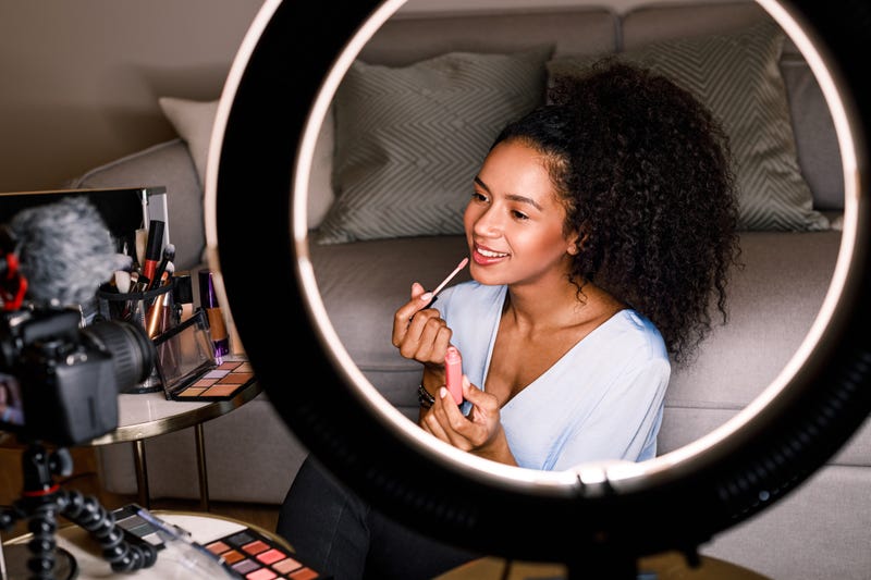 Woman recording makeup tutorial with DSLR camera and ring light