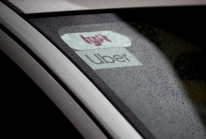 The Uber and Lyft logos displayed on a car.