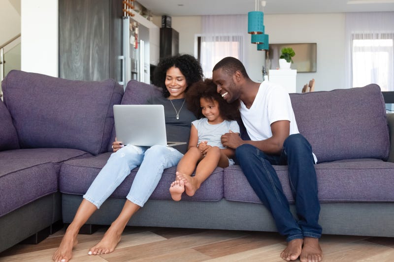 Parents and a daughter sit with a laptop on a couch