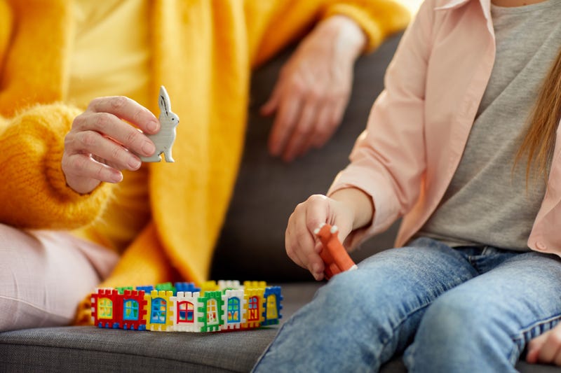 Closeup portrait of unrecognizable woman building house while playing with little girl at home, copy space