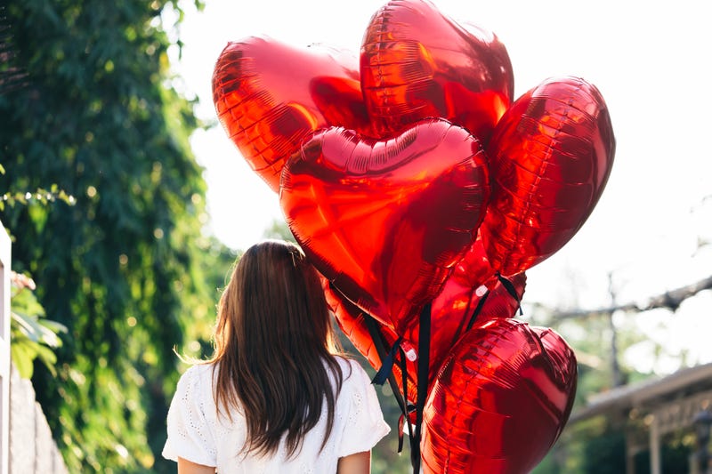 Unrecognizable woman with heart balloons on sunny day - stock photo