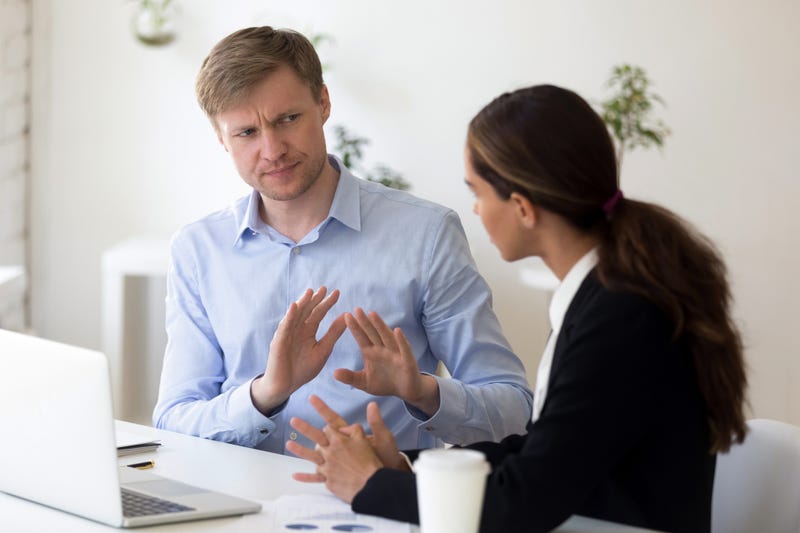A businessman rejects a woman sitting close using hid hands to motion her away