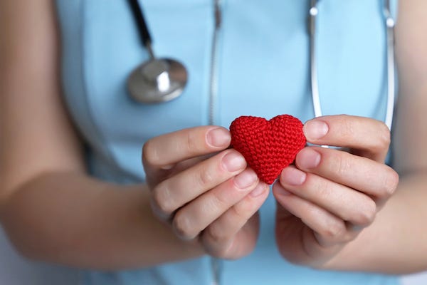 Female doctor holding red knitted heart in hands