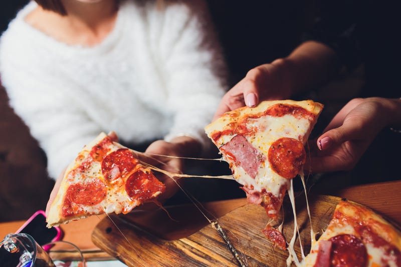 People pulling out two slices of pizza