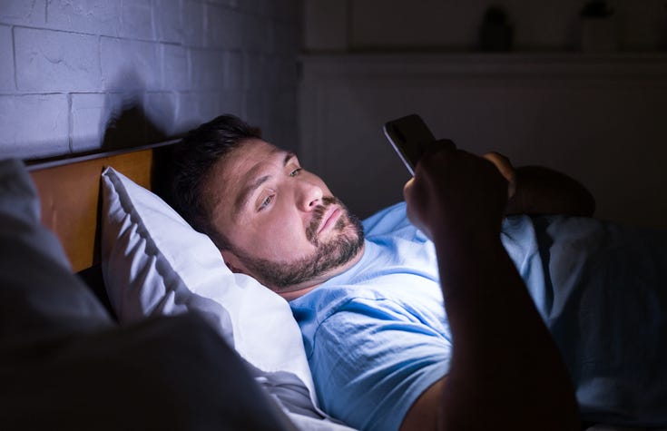 Man texting in bed