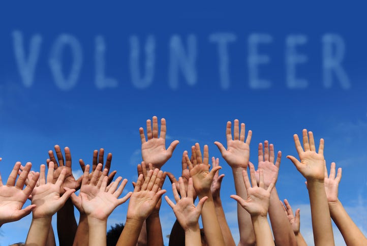 Multiethnic hands raised under word "volunteer