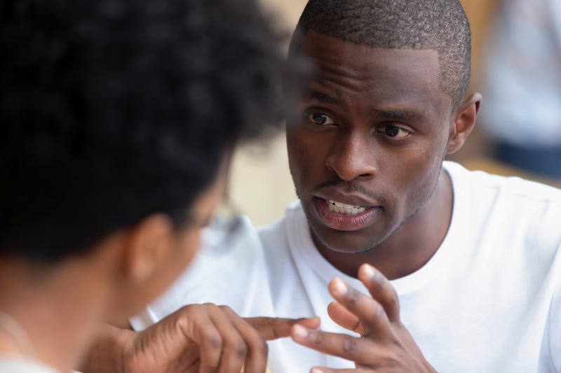 man in serious conversation with another individual, using hands to gesture