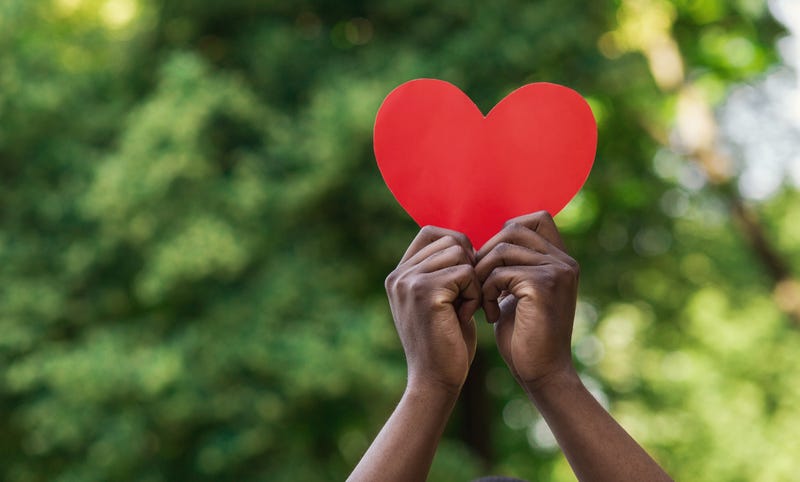 Black hands holding up a red heart 