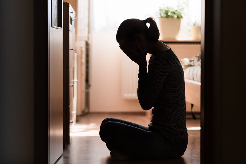 Silhouette of a woman with her face in her hands. 