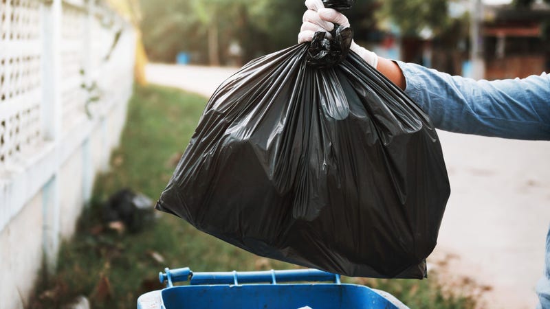hand holding garbage black bag putting in to trash