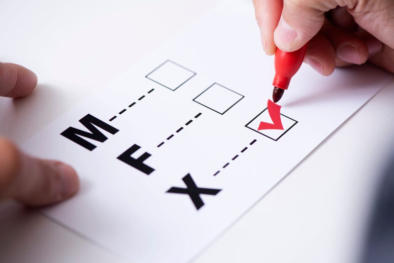 person marking the X in a form with the letters M for male, F for female and X for the third gender category