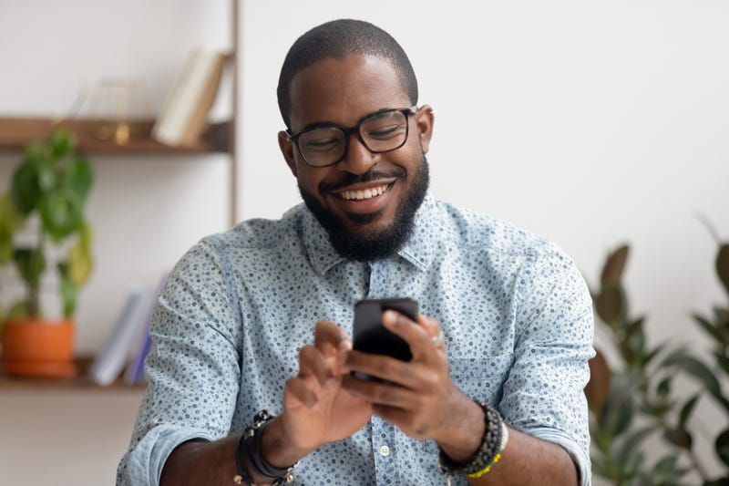 A man laughs at his phone while texting