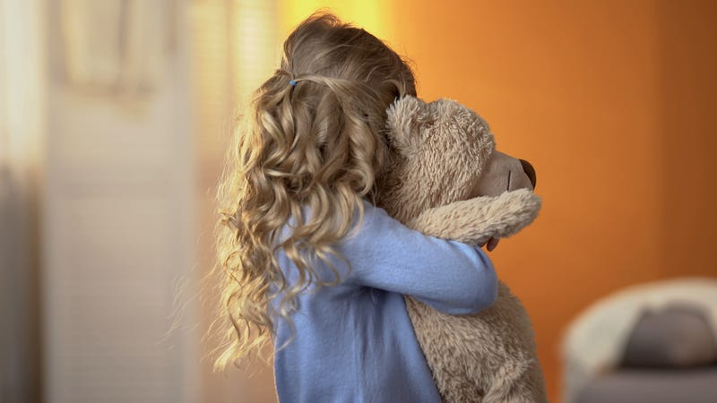 Orphaned child hugs her teddy bear.