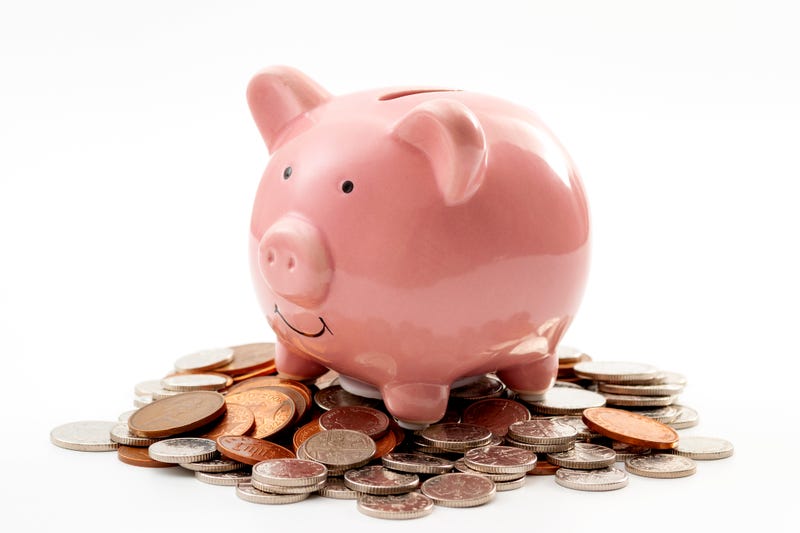 Save money, financial planning of personal finances and being thrifty concept theme with a pink piggy bank sitting on a pile of bronze and silver colored coins isolated on white background