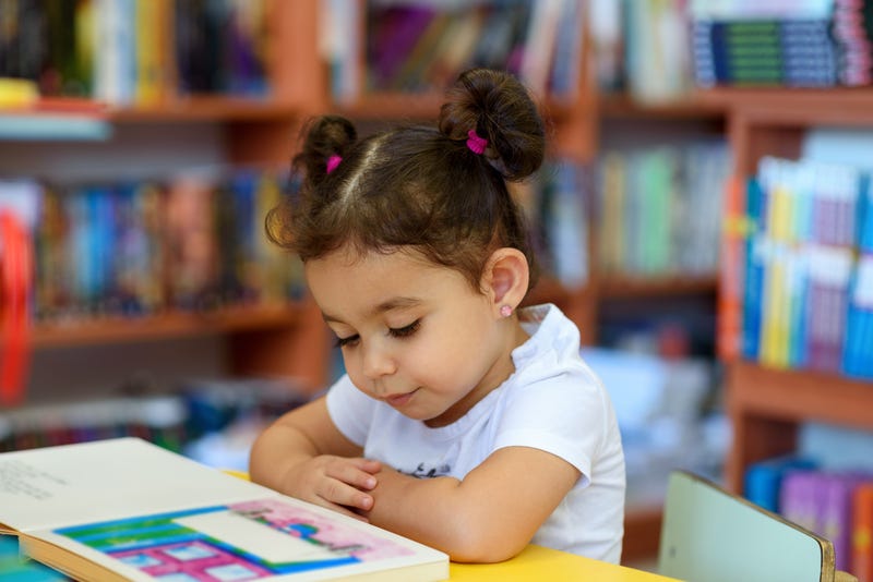 young girl reads a book in a school library