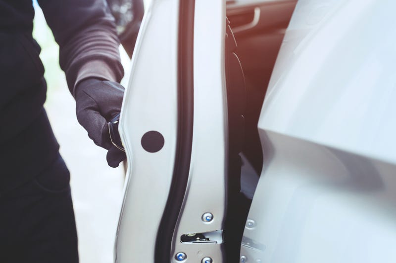 A gloved hand opens a car door.