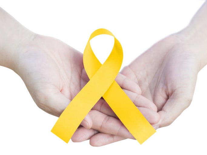  childhood cancer awareness  gold ribbon on hands isolated on white background