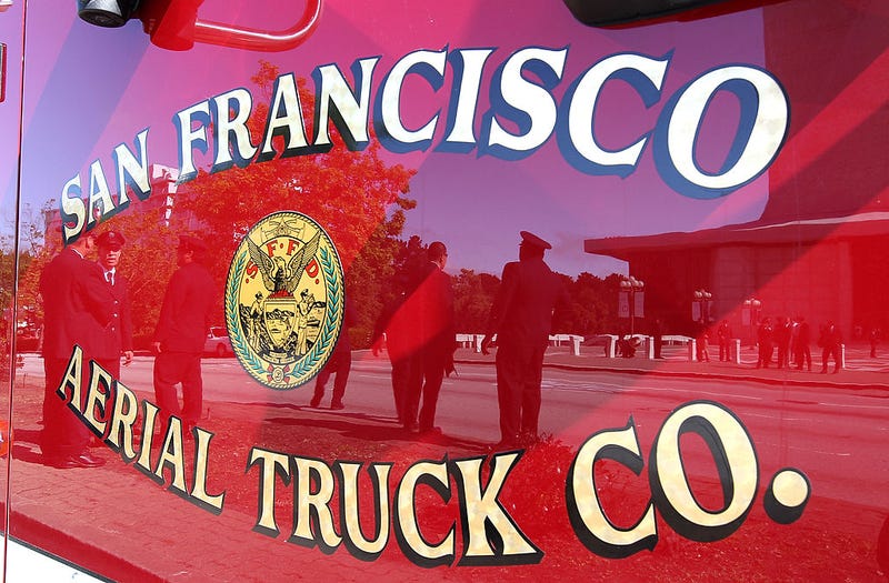 San Francisco firefighters are seen reflected in the door of a San Francisco fire truck June 10, 2011 in San Francisco, California.