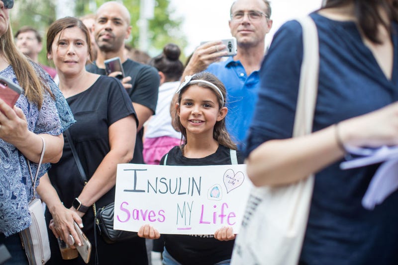 A girl holds a sign that reads "Insulin Saves My Life" while Democratic presidential candidate, U.S. Sen. Bernie Sanders (D-VT) talks about the cost of insulin in the USA versus Canada as he joins a group of people with diabetes on a trip to Canada for affordable Insulin on July 28, 2019 in Windsor, Canada.