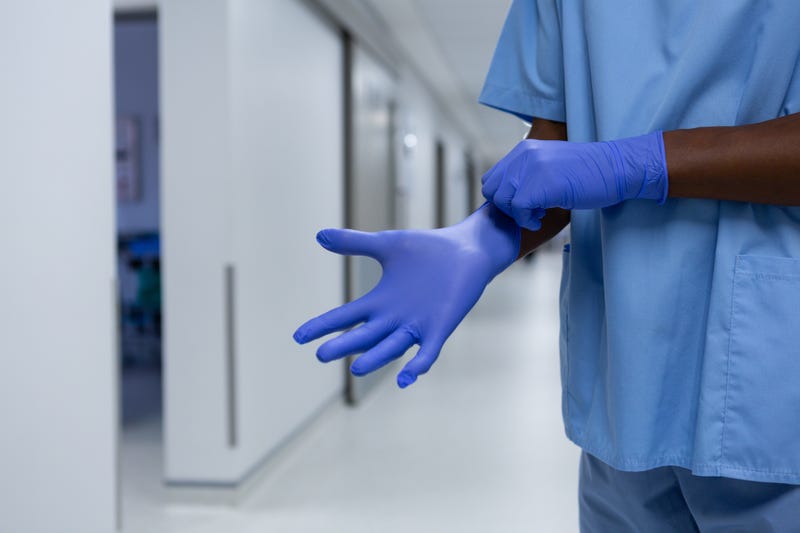 African-american male surgeon wearing surgical gloves in the corridor at hospital