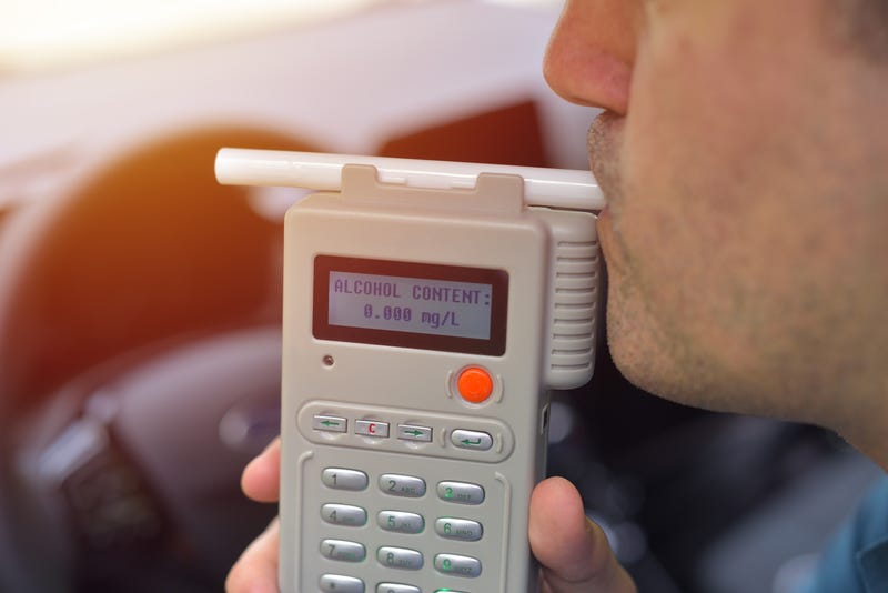 Man blows into breathalyzer in vehicle
