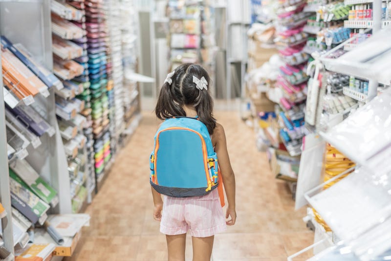 little girl in store with backpack ready for by school