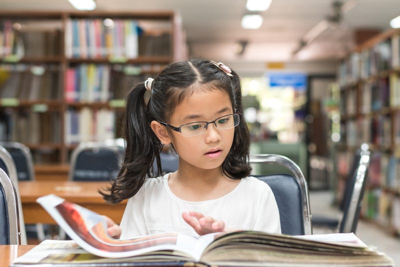 Young girl reading a book in a library