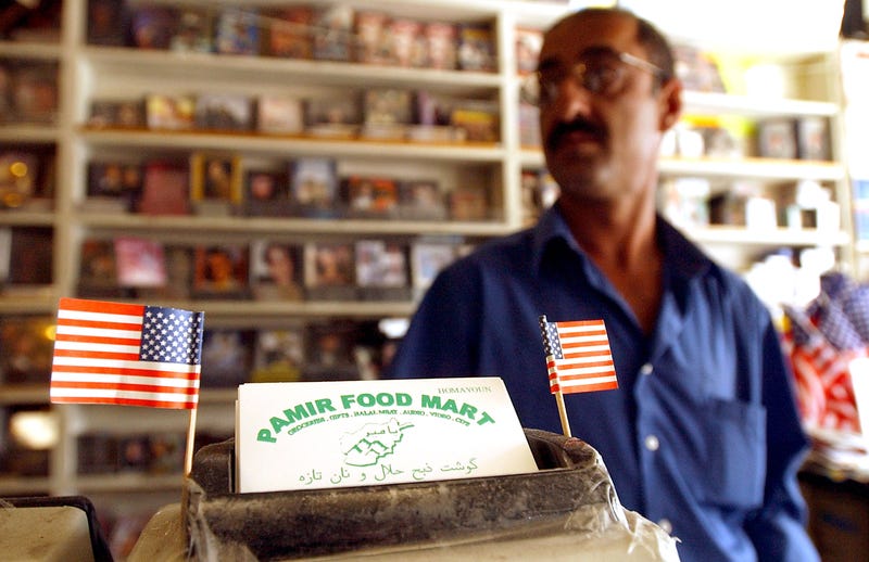 Shopkeeper Homayoun Khamosh displays American flags next to his business cards October 24, 2001 at the Pamir Food Mart in the "Little Kabul" district of Fremont, CA. 