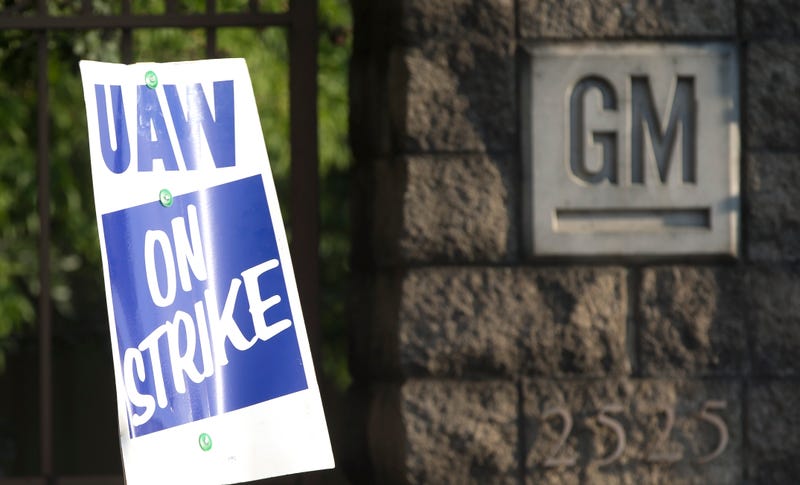 UAW strike sign and GM logo