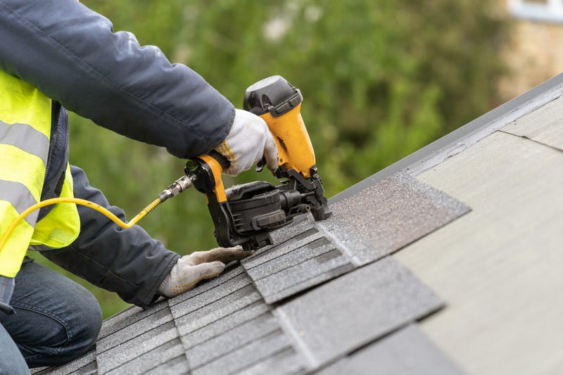 Roofer worker in uniform work wear using air or pneumatic nail gun