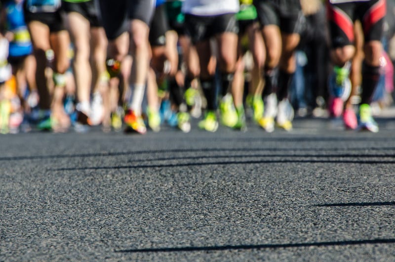 Asphalt with legs bottom of runners during a marathon 