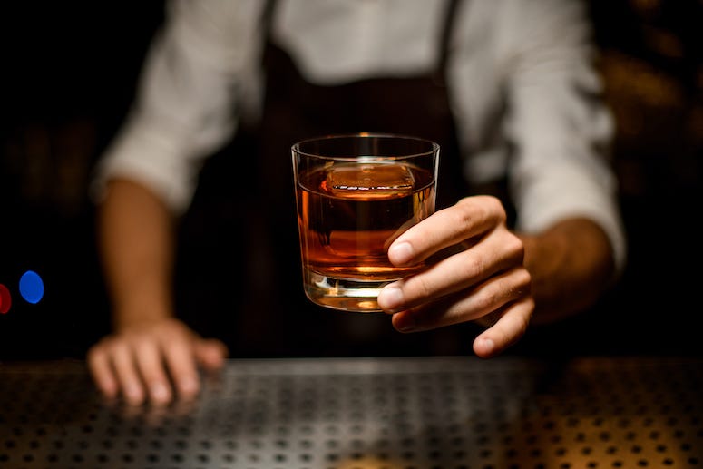Bartending serving glass of whiskey