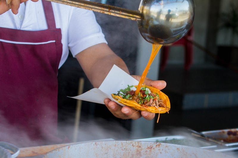 cook pours sauce on taco