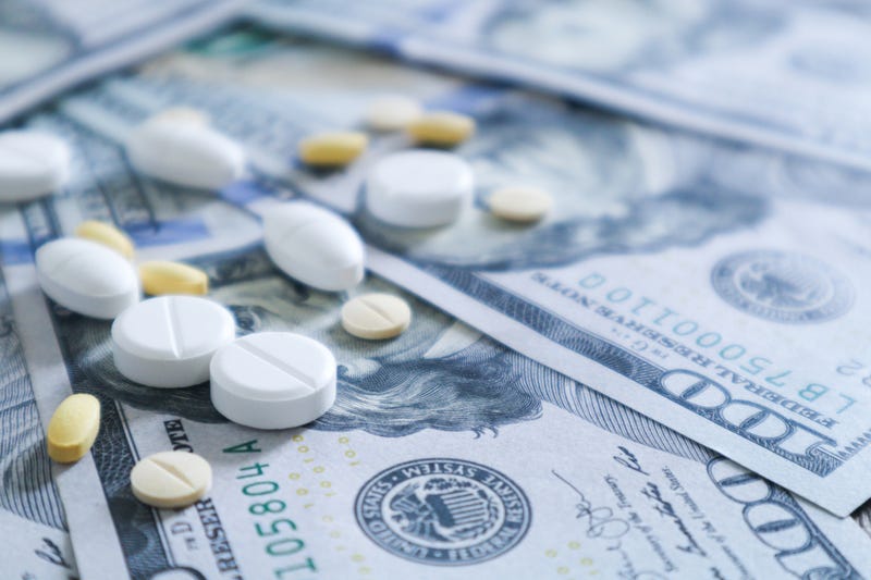 Medicine on top of hundred dollar bills.