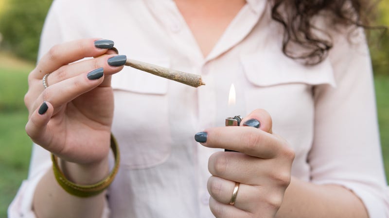Person lighting up a marijuana joint outside. 