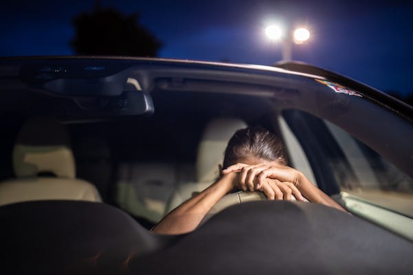 Woman sleeping on her steering wheel inside her car