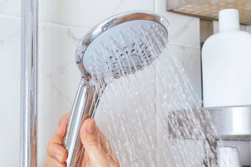 Woman hand using shower head in bathroom