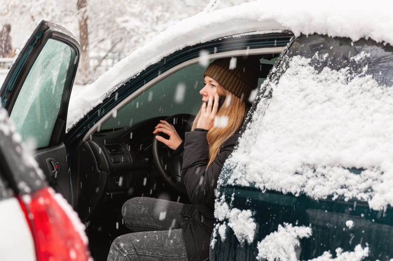 Woman on the phone in car covered in snow 